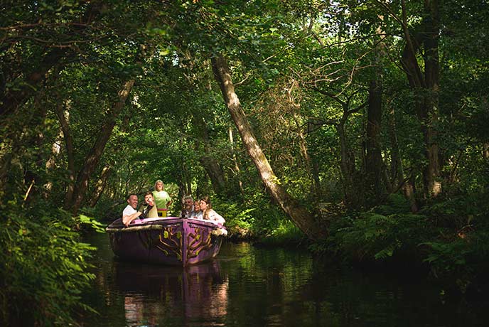 A family enjoying a boat ride through some trees at BeWILDerwood in Norfolk