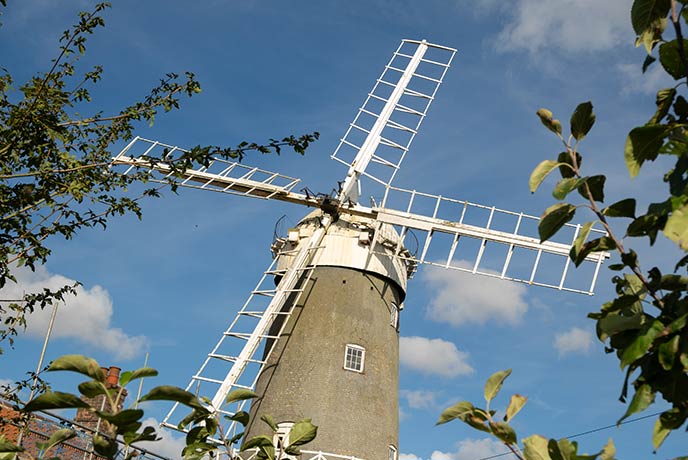 The historic Bircham Windmill through a gap in the trees in Norfolk