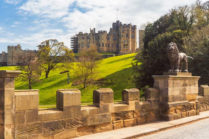 Looking across the road and fields at the towering Alnwick Castle in Nortumberland