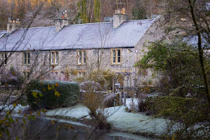 A pretty row of stone houses with gardens frosted over