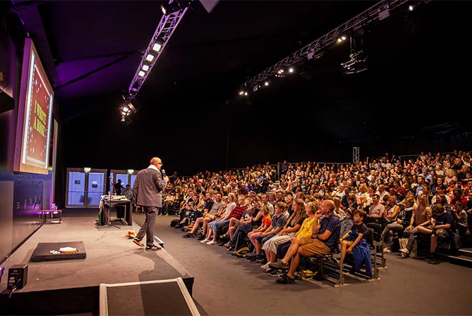 Someone giving a talk to a large audience at the https://www.classic.co.uk/browse-holiday-cottages/UK--1.html