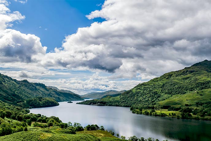 Looking out across green mountains and blue waters of Loch Lomond in the Scottish Highlands