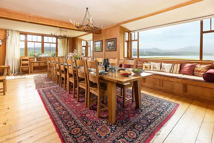 The large wooden dining room with views over water at Cape Wrath Lodge in the Scottish Highlands