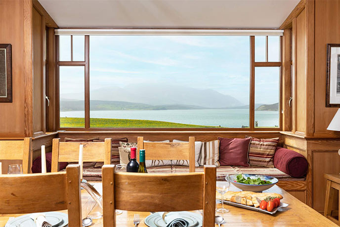 Looking across the dining table at Cape Wrath Lodge at the water and mountains beyond the window