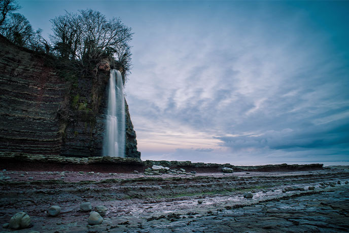 A waterfall cascading down the cliff at St Audries Bay in Somerset
