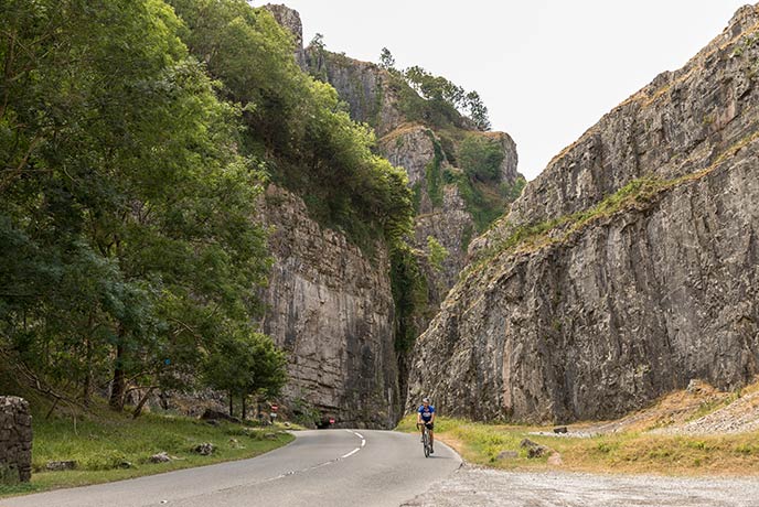 Someone cycling through the dramatic valley at Cheddar Gorge in Somerset