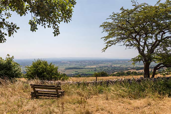 A wooden bench looking over a patchwork of fields across the Mendip Hills in Somerset