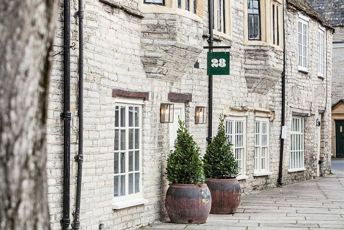 Looking down a street of beautiful stone-work buildings with the 28 sign over two bushes