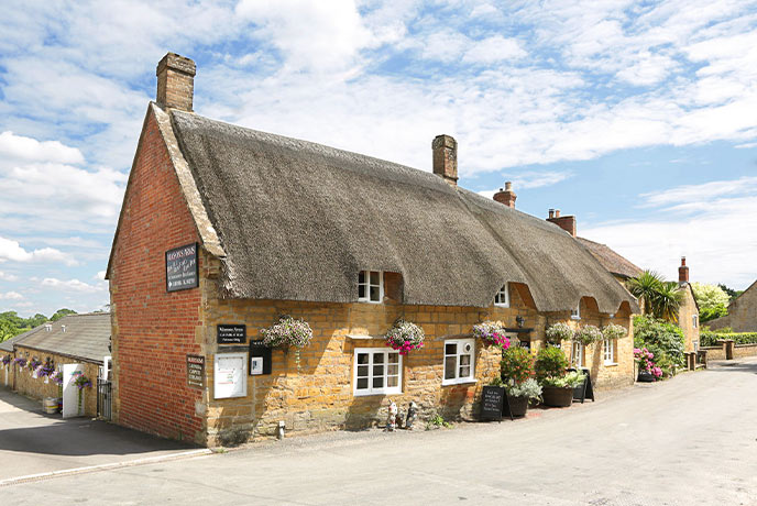 The golden bricked and thatched exterior of The Masons Arms inn Somerset