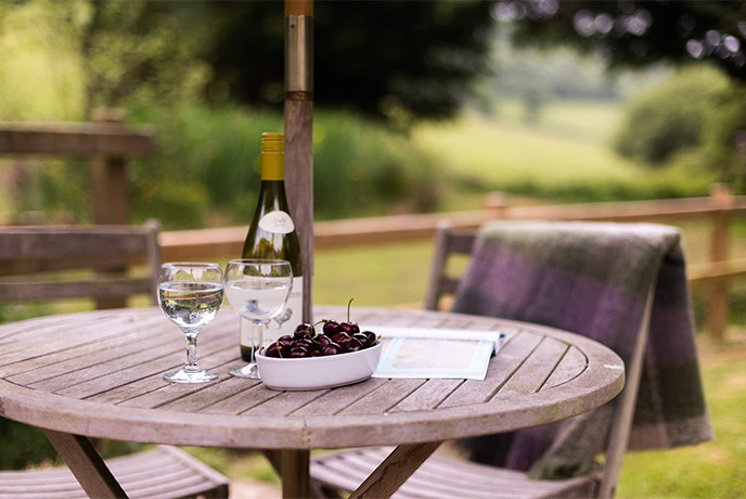 A wooden outdoor table at Dieppy Farm Cottage surrounded by the countryside