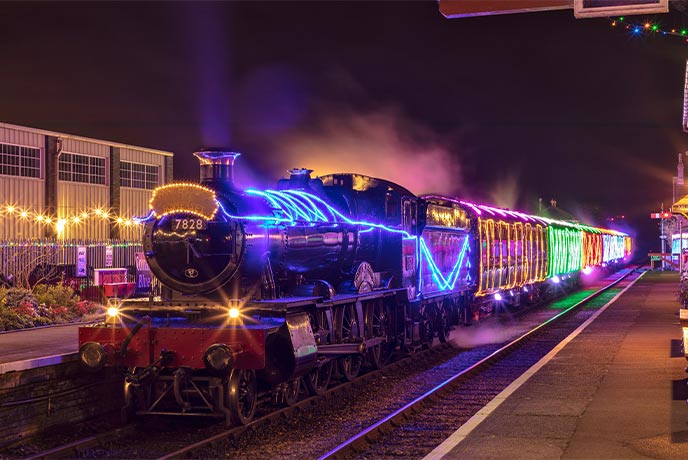 A steam train covered in Christmas lights at West Somerset Railway