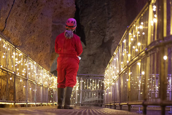 Someone standing in a corridor of Christmas lights at Wookey Hole in Somerset