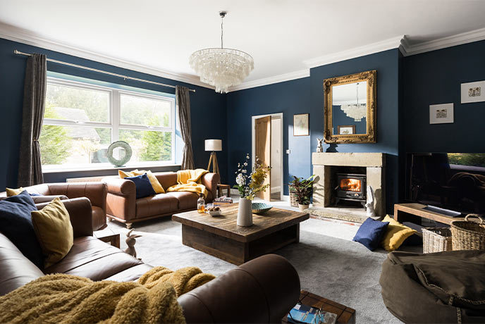 The sleek sitting room with deep blue walls at Wetley Abbey Cottage in Staffordshire