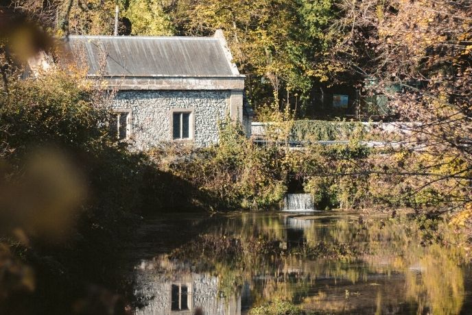 A traditional cottage reflected in the surface of Swanbourne Lake in Arundel