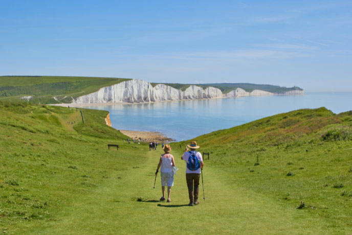 Two people walking along the chalk cliffs of the Seven Sisters in Sussex