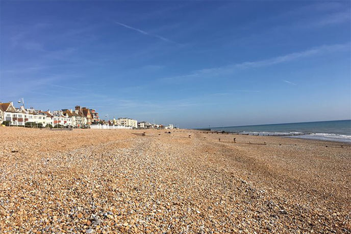 The stretching shingle beach and blue waters at Bexhill beach in East Sussex