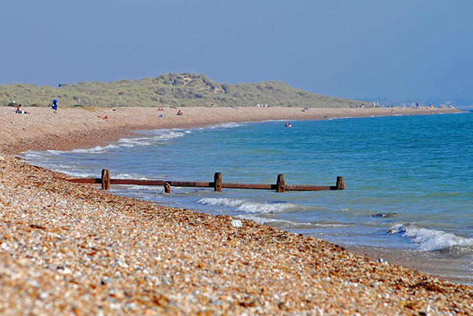 Looking down along the shingle and pebble beach of Climping with groynes running down to the sea