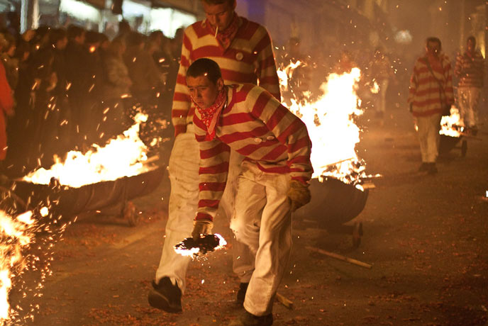 People in red and white striped clothing with burning torches at Lewes Bonfire Night