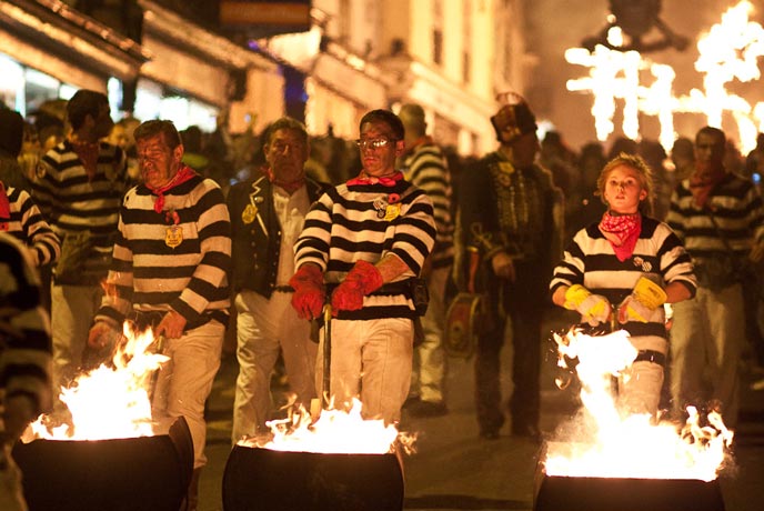People dressed in black and white clothes with burning barrels at Lewes Bonfire NIght
