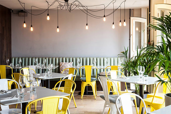 The sleek interior of Murmur, with yellow chairs and hanging lights