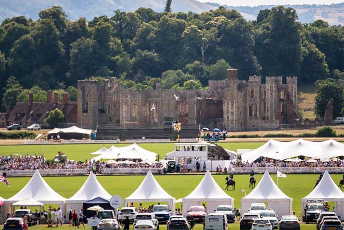 Looking over some tents at people playing polo at Cowdray Estate with the ruins of the castle in the background