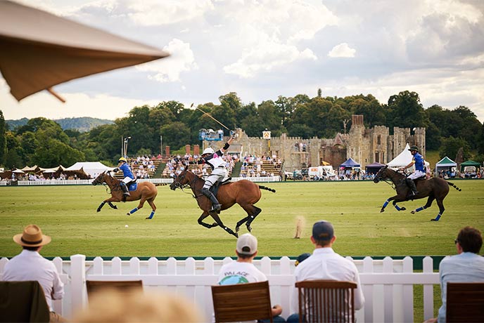 People playing polo at Cowdray Park Polo Club with the ruins of Cowdray Castle in the background