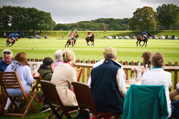 People sat on deck chairs watching polo at Cowdray Park Polo Club