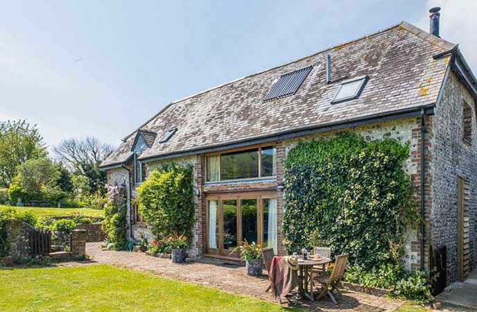 The pretty, ivy-covered Acorn Barn, with a lovely lawn and al fresco dining table