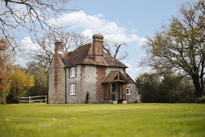 The quaint, stone exterior of Apsley Cottage surrounded by green grass and trees