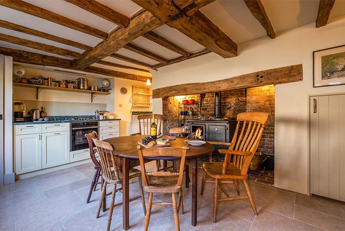 The beautiful kitchen and dining room at The Pigeon House, with expose beams and a gorgeous wood-fired range