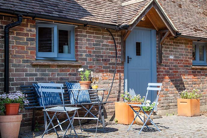 The pretty red brick exterior of The Tea Hut, with a blue door and outdoor table and chairs for some alfresco dining