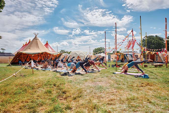 People performing downward facing dog during a yoga workshop at the Love Supreme Festival in Sussex