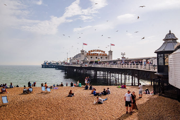 People having fun on the sand beneath Brighton Pier