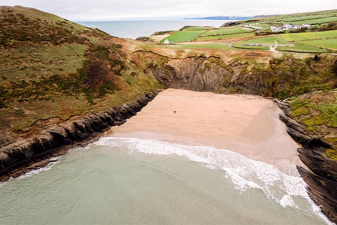 The golden sands and towering cliffs at Mwnt Beach in Wales