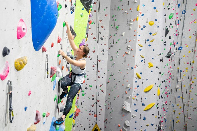 A woman climbing up the wall at Beacon Climbing Centre in Gwynedd
