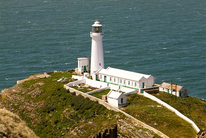 The bright white Stack House Lighthouse perching on the cliffs in Wales