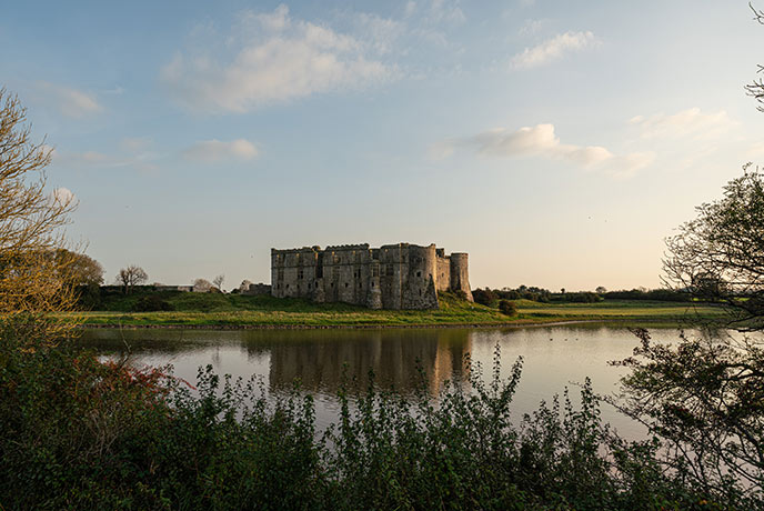 The impressive Carew Castle surrounded by water at sunset, one of the best castles in Pembrokeshire