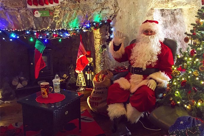 Father Christmas sat in his grotto at Pembroke Castle in Pembrokeshire