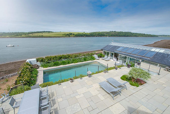 Looking out over the terrace at the swimming pool and estuary beach beyond at Beach House in Pembrokeshire