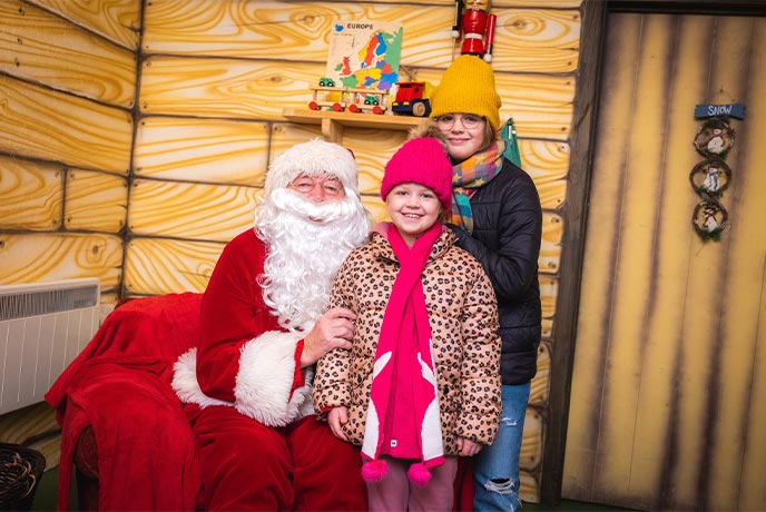 Father Christmas sitting next to two children at Folly Farm's Santa's Grotto