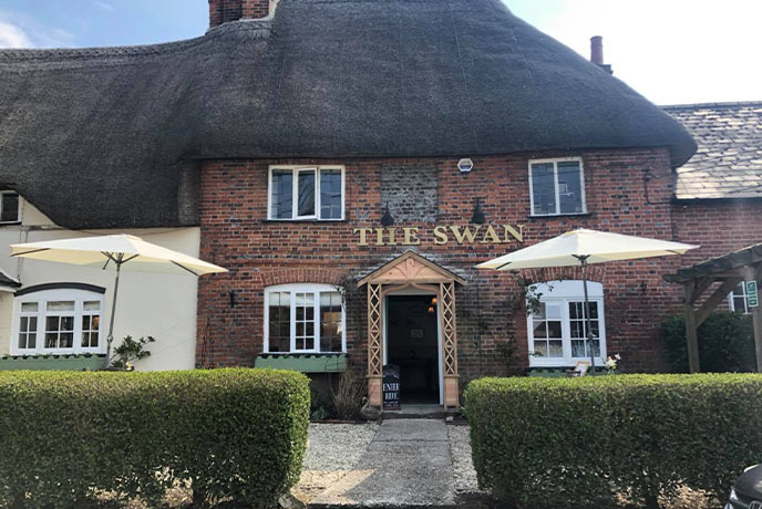 The thatched and red bricked exterior of The Swan Inn in Wiltshire