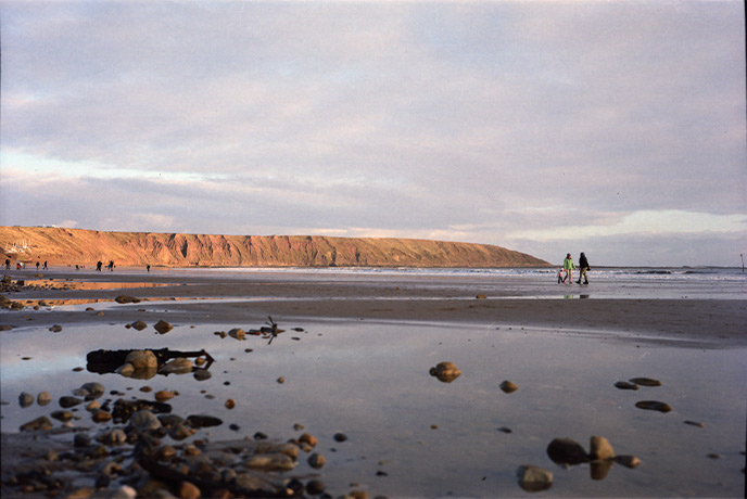 People walking across Filey Beach with the cliffs in the background