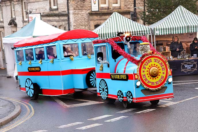 A festive land train covered in tinsel going through the streets at Malton Christmas Market in Yorkshire