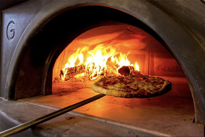 A pizza being taken out of a wood-fired pizza oven at La Trattoria in Malton
