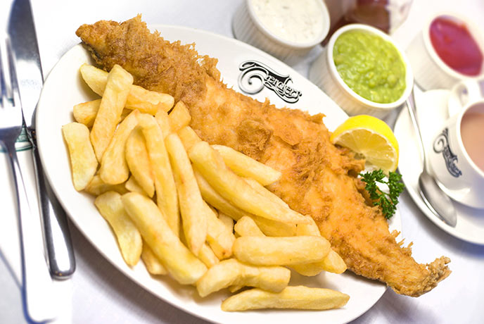 A plate of fish and chips with tartare sauce and mushy peas and cup of tea at Trenchers in Yorkshire