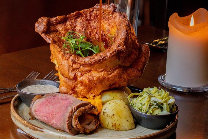 A giant Yorkshire pudding alongside a roast dinner and a candle at The Star Inn The City in Yorkshire