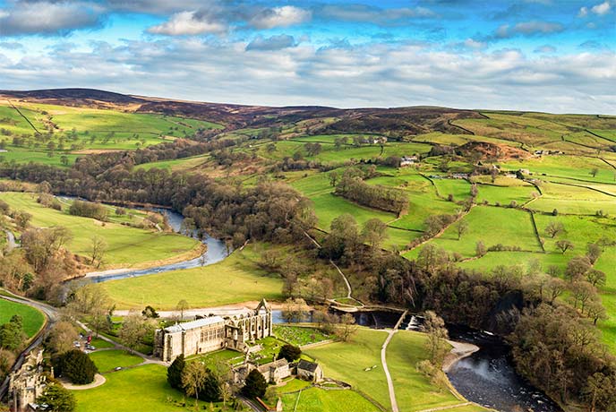 A bird's eye view of the ruins of Bolton Abbey and surrounding fields in Yorkshire