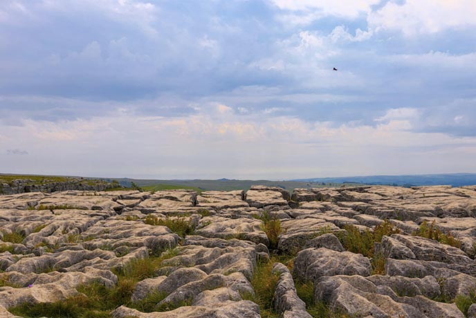 Looking across the stepping stone-like rocks at the sprawling countryside below at Malham Cove in Yorkshire