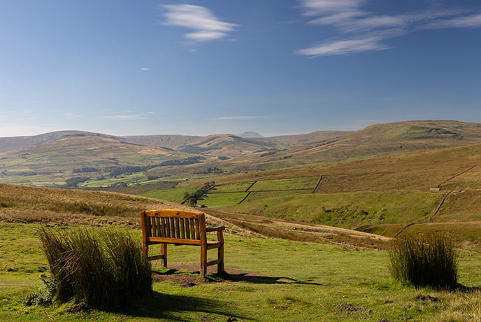 A wooden bench overlooking the rolling countryside of the Yorkshire Dales from Abbotside Common to Widdale Fell