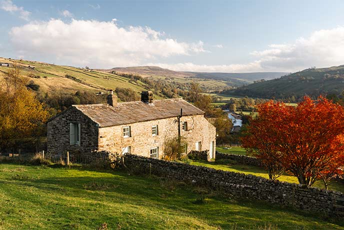 The beautiful stone cottage of Nettlebed surrounded by rolling countryside and autumnal trees in Yorkshire